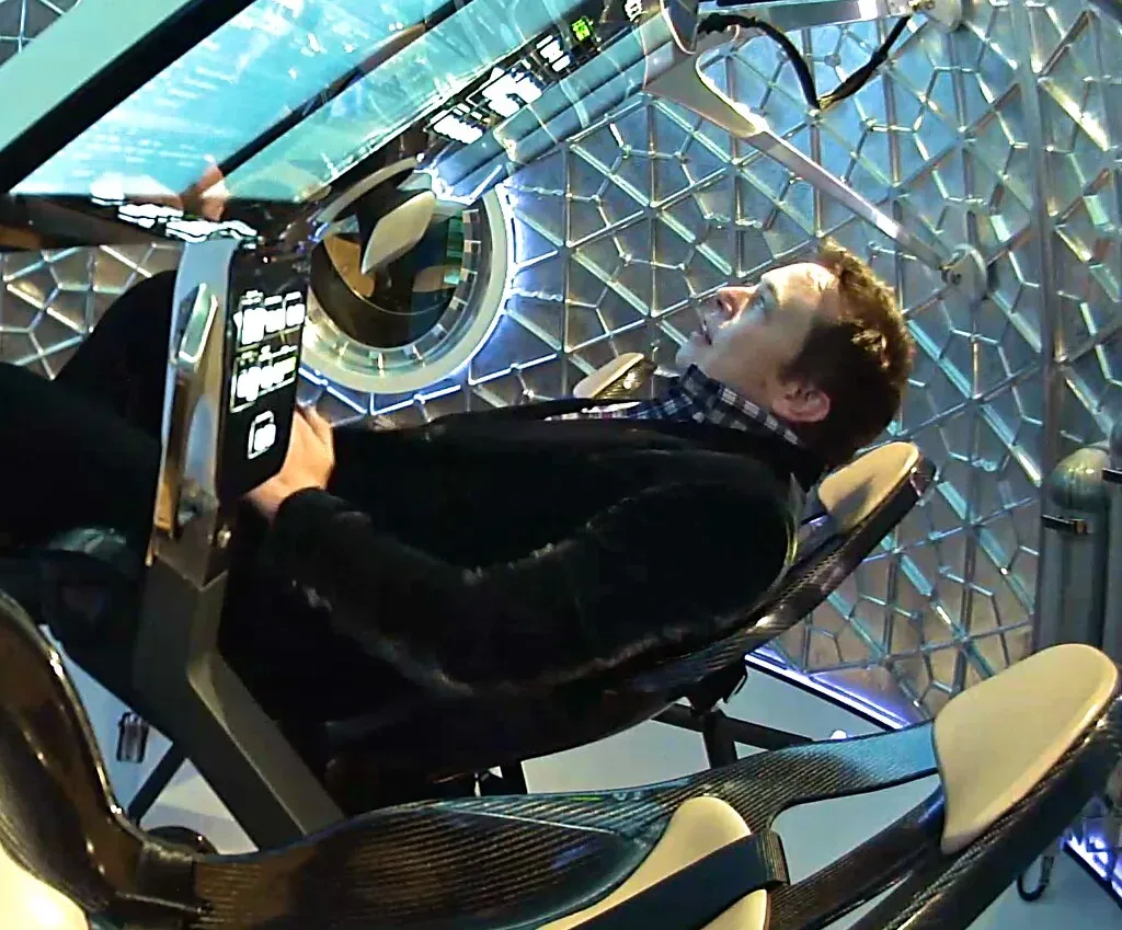 Un hombre reclinado en el interior de una cápsula o simulador espacial futurista