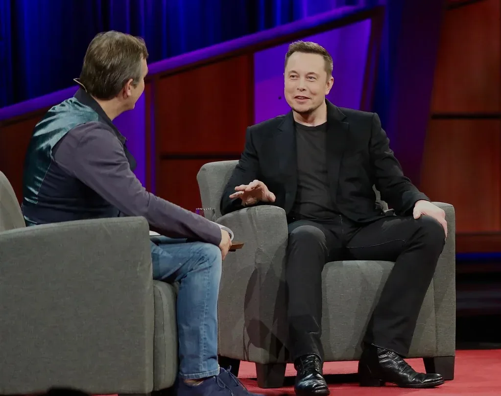 Elon Musk conversa con un entrevistador sentados en un escenario iluminado