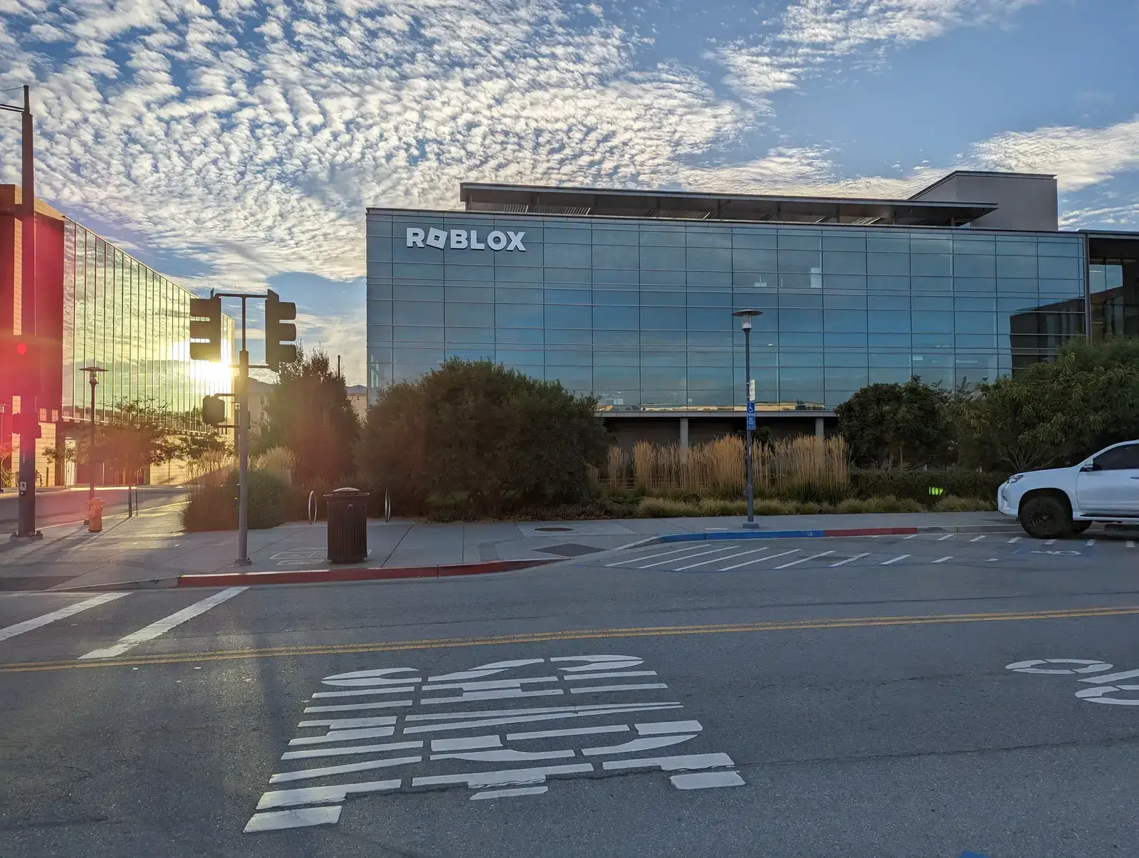 Fachada acristalada de la sede de Roblox con su logotipo al atardecer