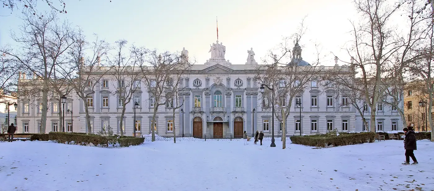 Fachada nevada del Congreso de los Diputados en Madrid con transeúntes