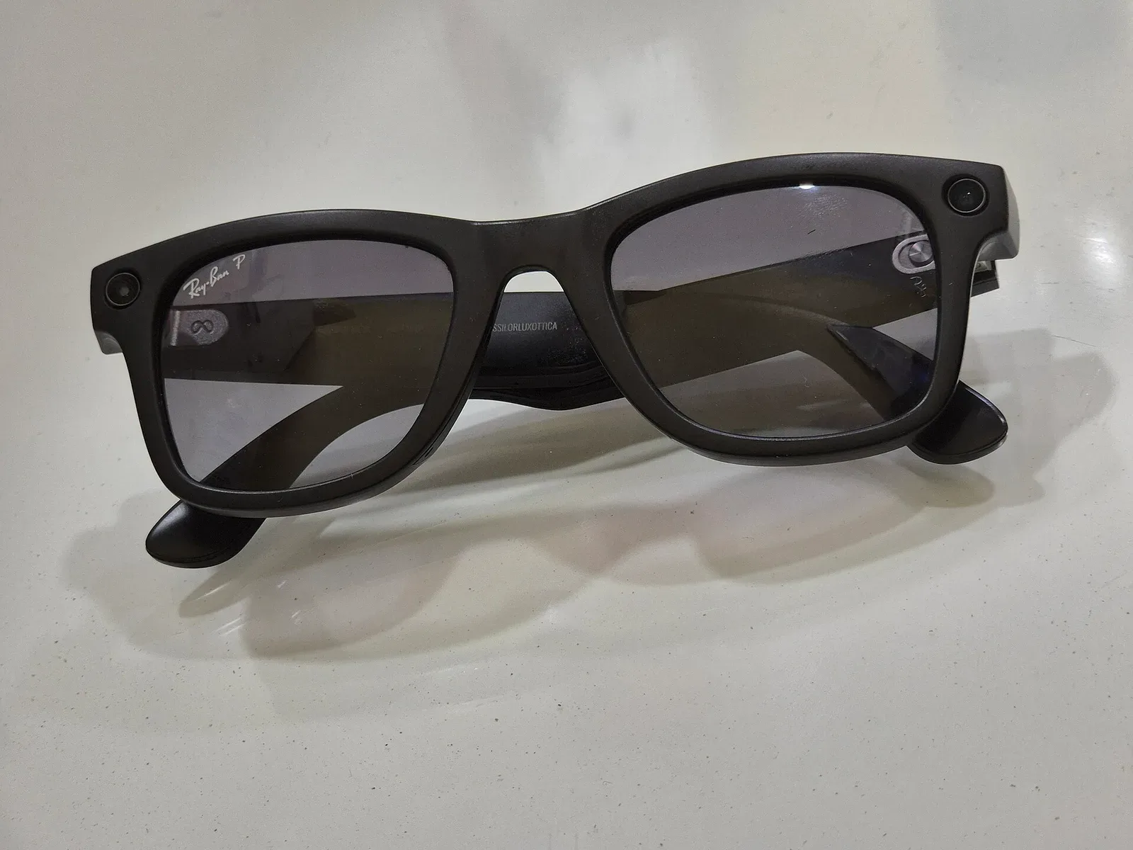 Gafas inteligentes Ray-Ban Meta con cámaras integradas sobre superficie blanca