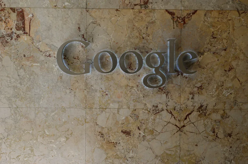 Logotipo metálico de Google instalado sobre una pared de mármol en una sede corporativa