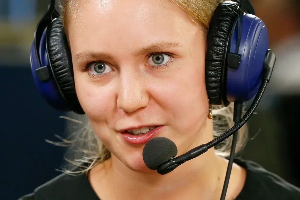 Mujer con auriculares y micrófono de diadema habla durante una transmisión o locución