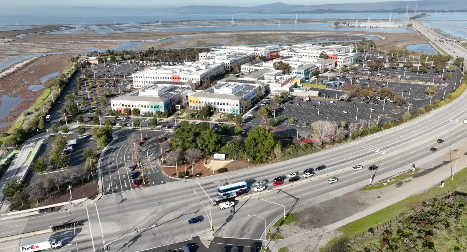 Vista aérea del campus corporativo junto a la bahía, con aparcamientos y autopista cercana
