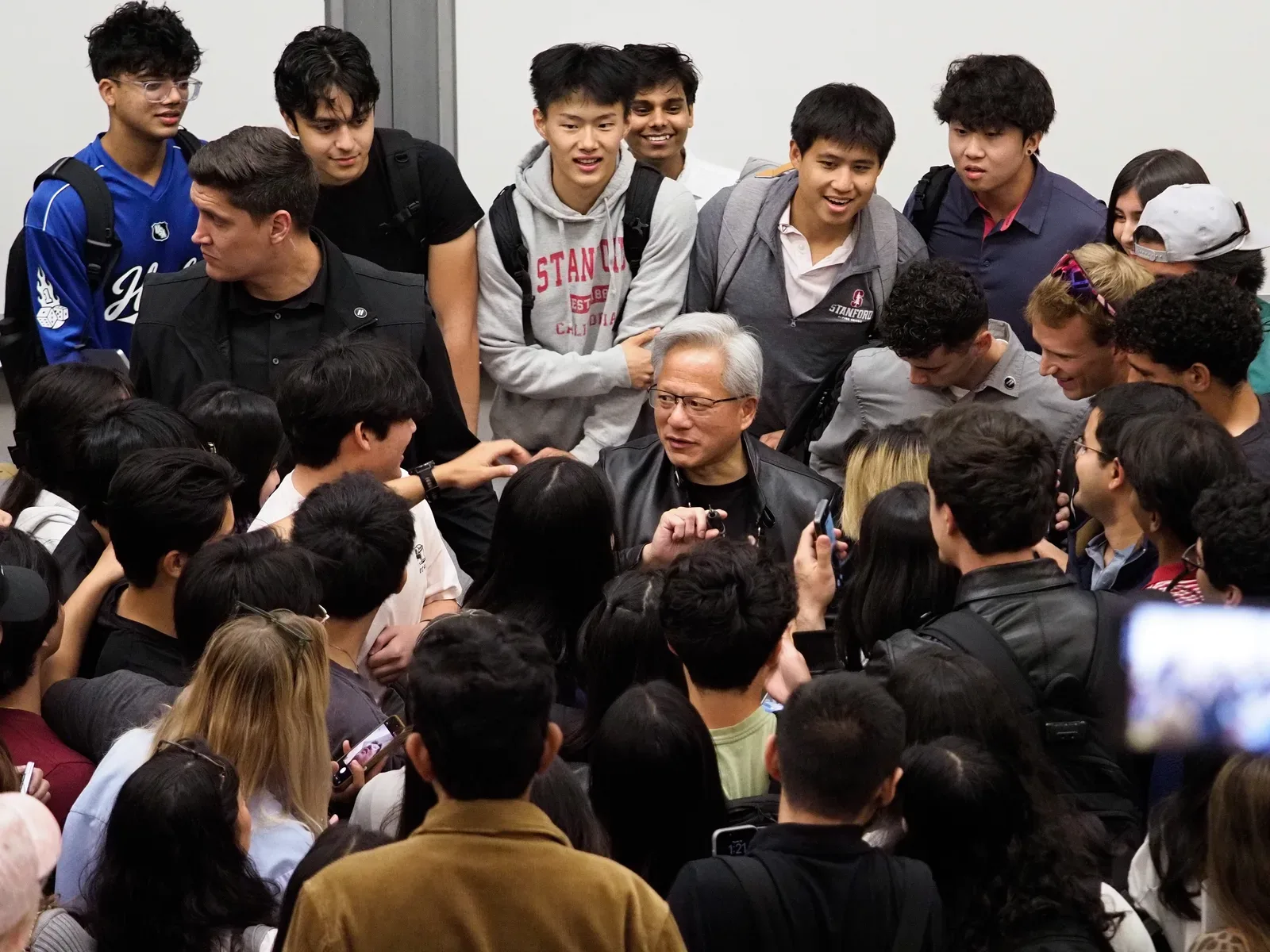 Jensen Huang, CEO de NVIDIA, rodeado de estudiantes en un evento en Stanford