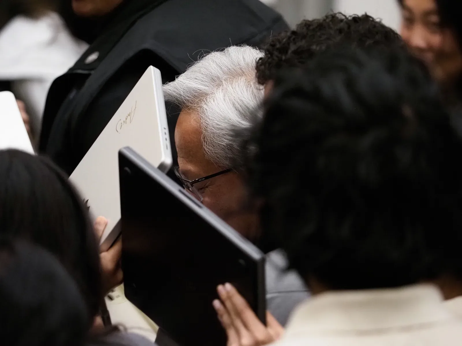 Personas entre el público sostienen portátiles abiertos en un evento concurrido