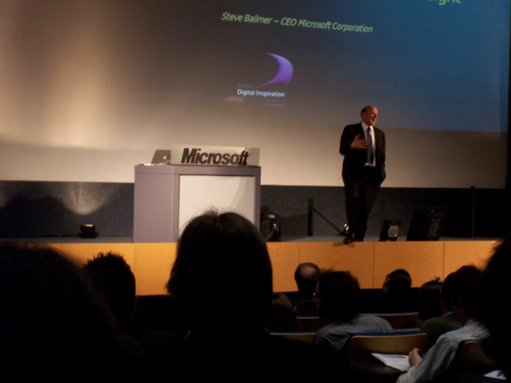 Hombre habla en un escenario junto a atril con el logo de Microsoft