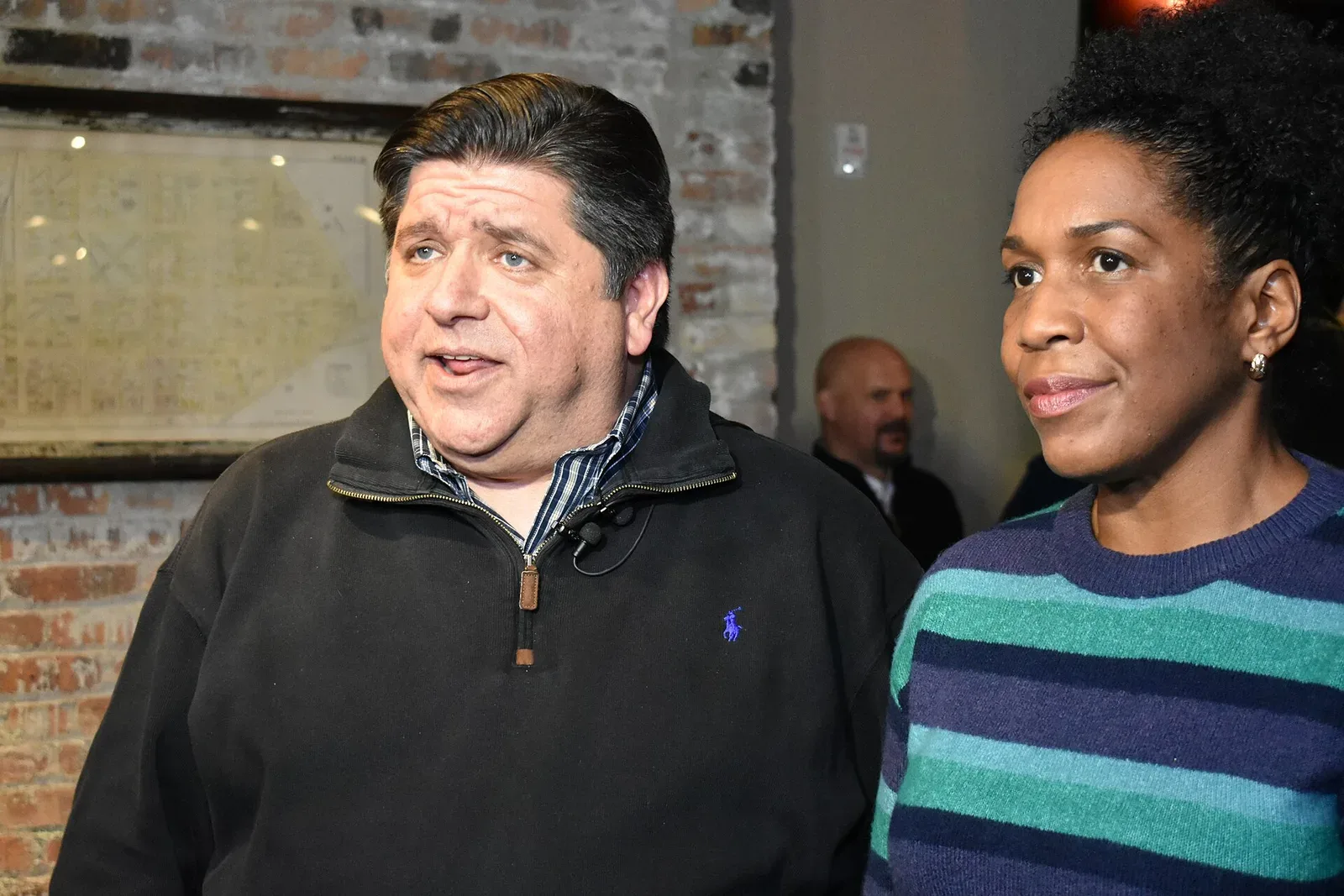 JB Pritzker conversa junto a una mujer en un acto público