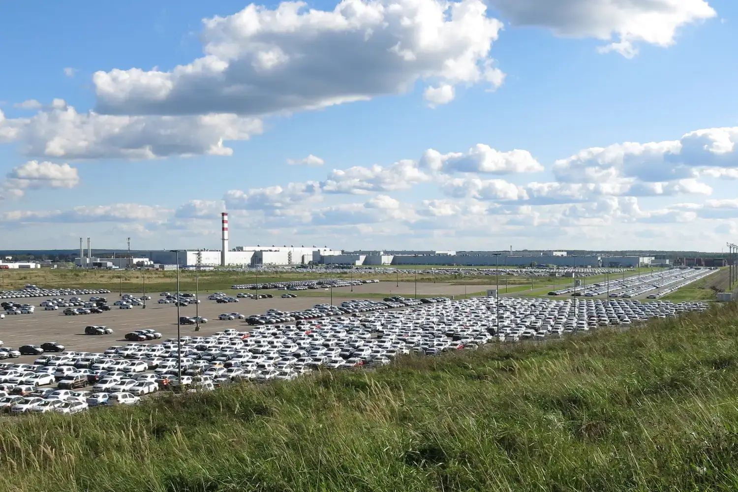 Miles de vehículos nuevos almacenados en explanada junto a planta industrial