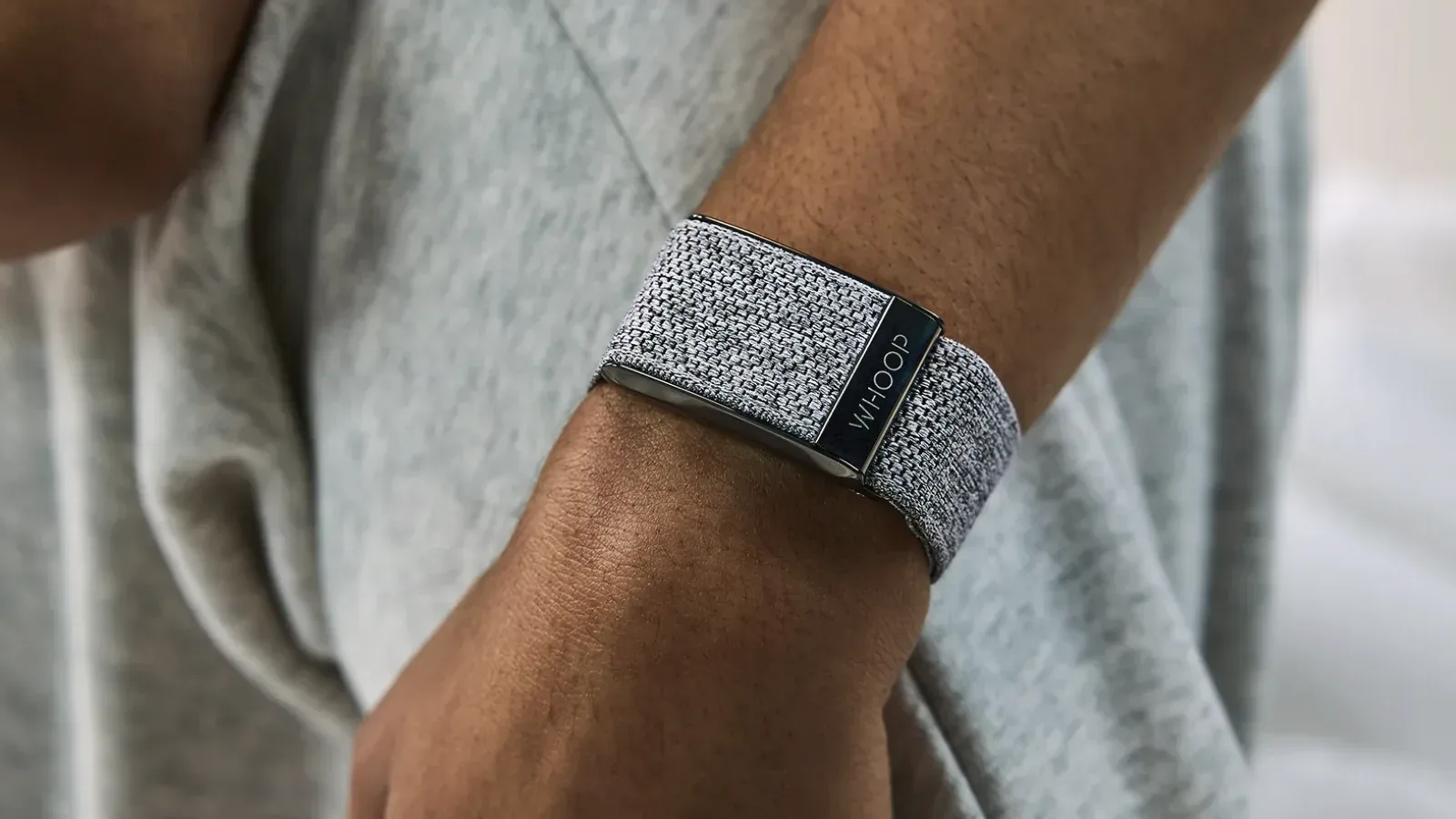 Pulsera WHOOP de tela gris colocada en la muñeca de una persona