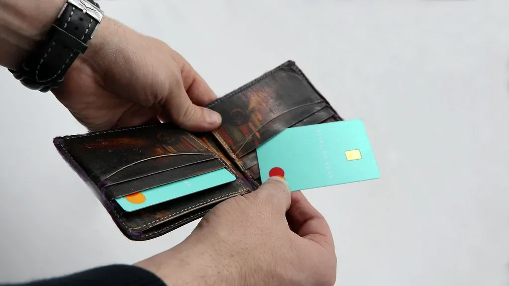 Una persona saca una tarjeta turquesa de Starling Bank de su billetera