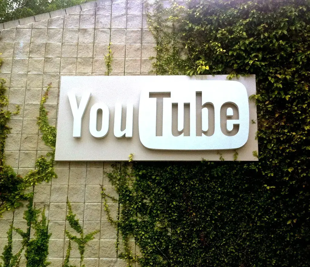 Cartel corporativo de YouTube en fachada cubierta de enredaderas