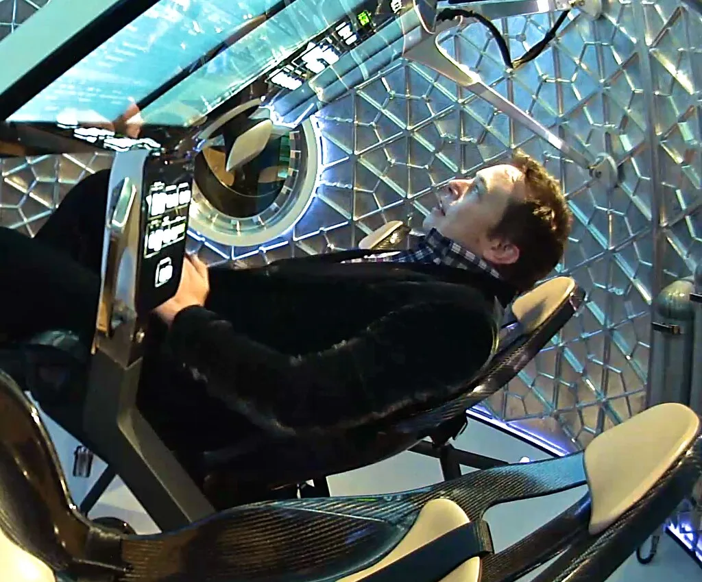 Un hombre reclinado en el interior de una cápsula o simulador espacial futurista