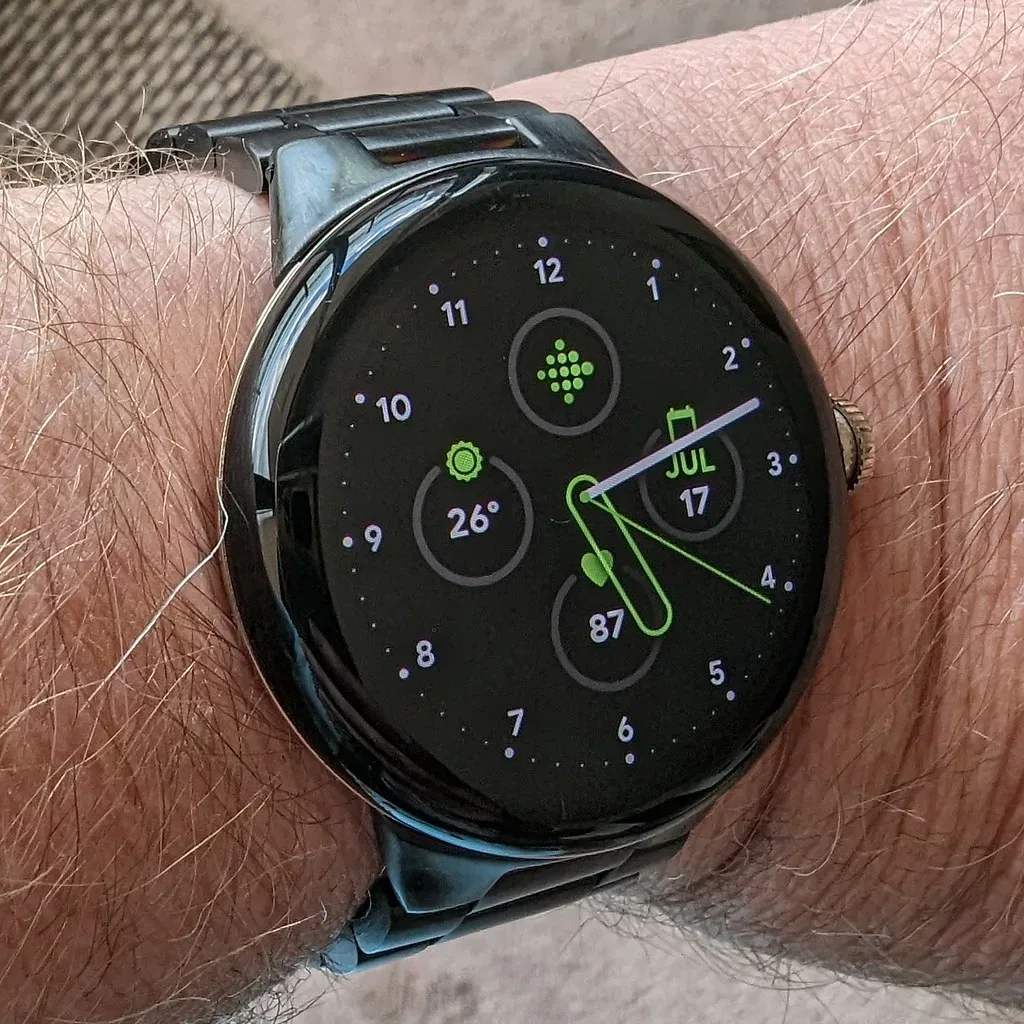 Reloj inteligente con esfera digital y correa metálica en una muñeca