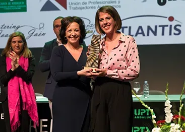 Dos mujeres sostienen un premio durante un acto de UPTA en un escenario