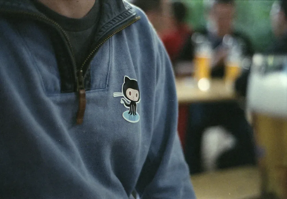 Pegatina de la mascota Octocat de GitHub sobre una chaqueta, en una reunión informal