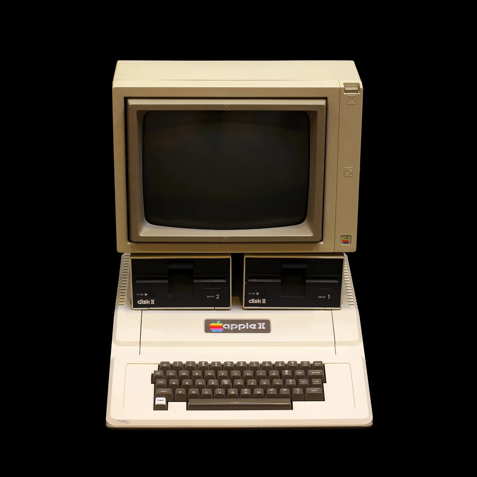Equipo Apple II vintage con monitor y doble disquetera en fondo negro