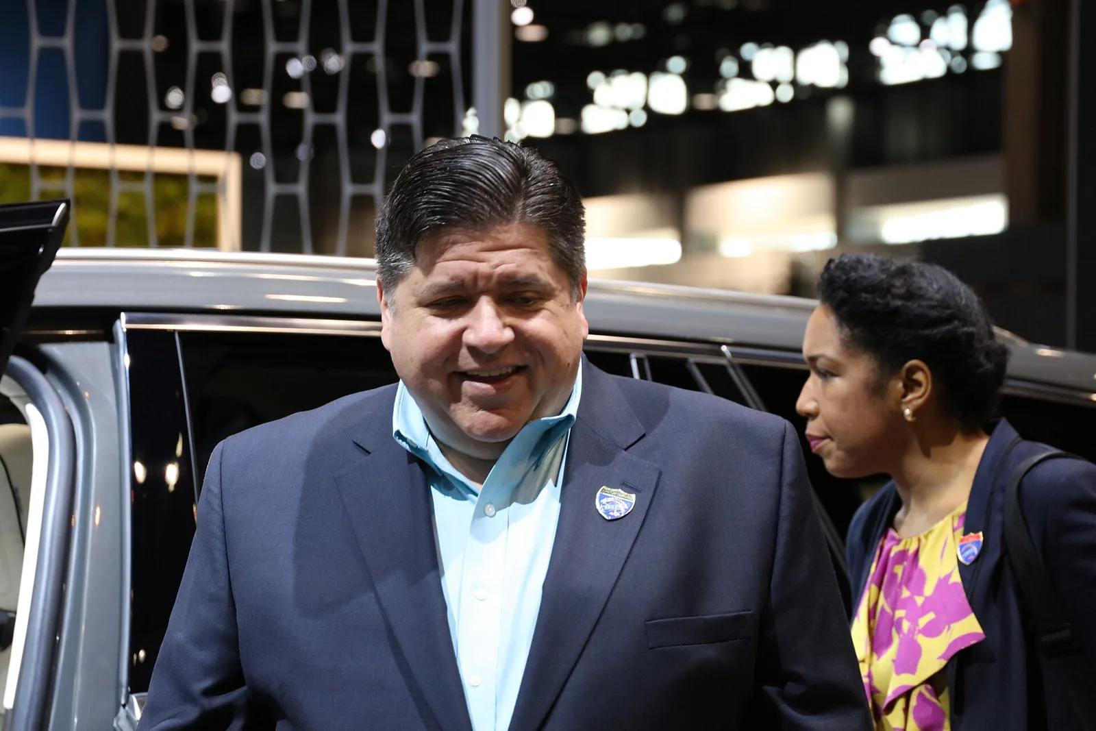 El gobernador JB Pritzker baja de un vehículo acompañado de una mujer