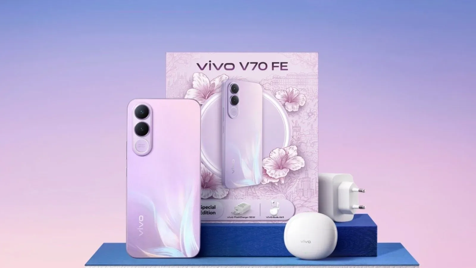 El vivo V70 FE en rosa junto a cargador, auriculares y su caja edición especial