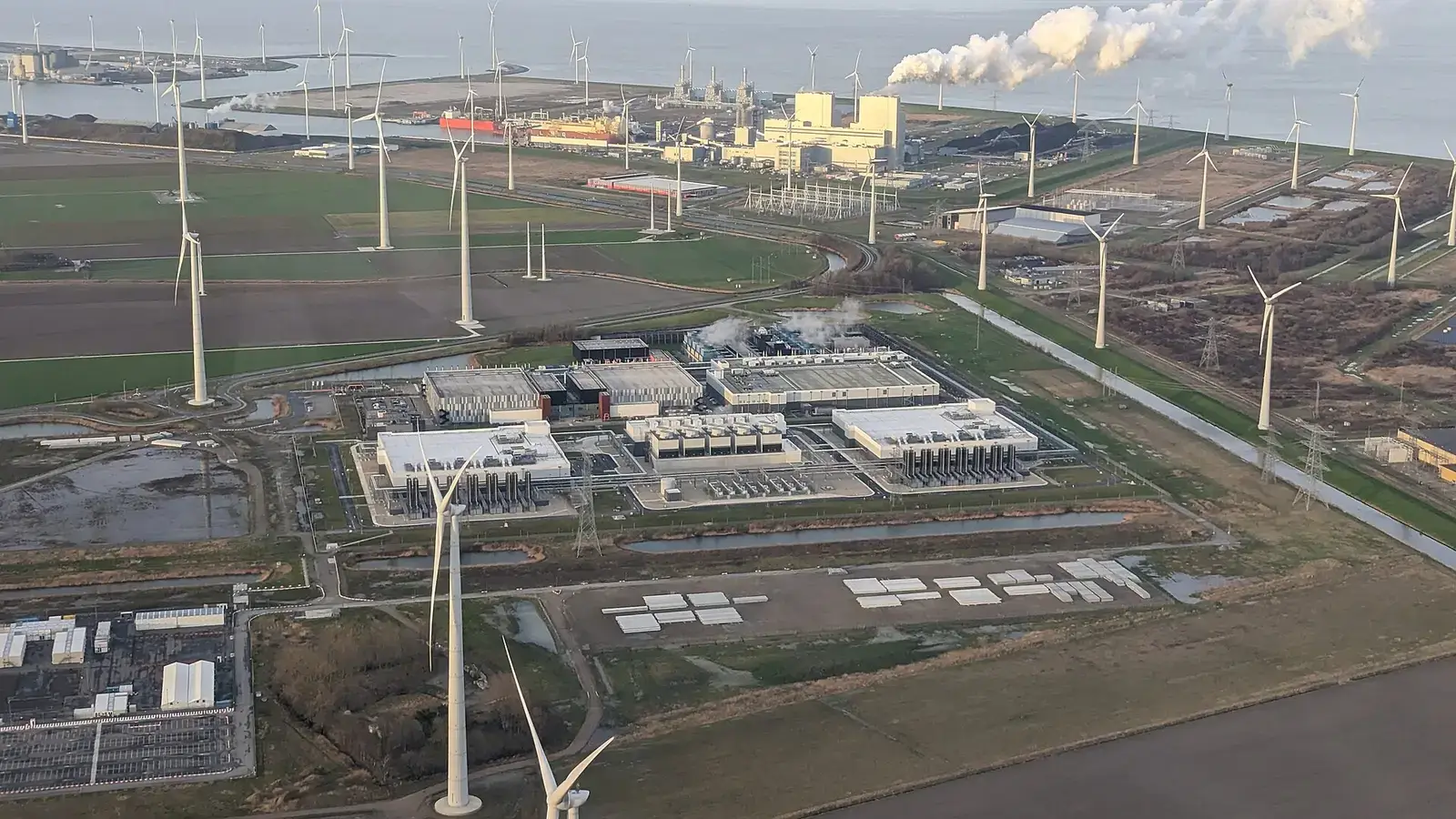 Vista aérea de un centro de datos junto a parque eólico y planta industrial